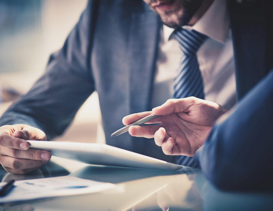 Image of two young businessmen using touchpad at meeting